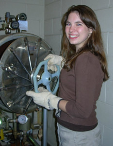 Photo of Monica Hartman holding the handle of the autoclave door