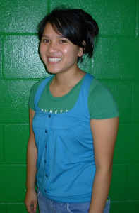 Photo of Trang Pham smiling in front of a green wall