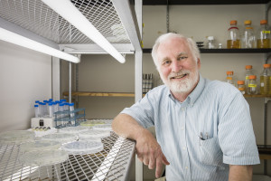 Photo of Dr. James Moroney in the lab posing with plates of C. reinhardtii