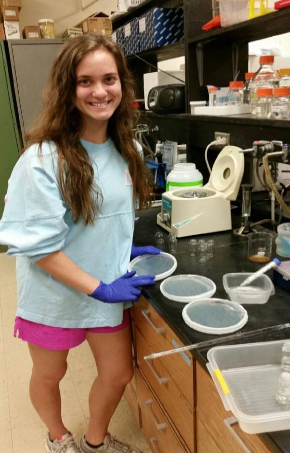 Undergraduate worker Kayla in the lab holding plates