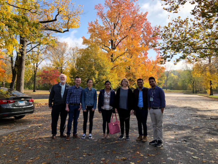 Members of the lab smiling and standing side-by-side in a park
