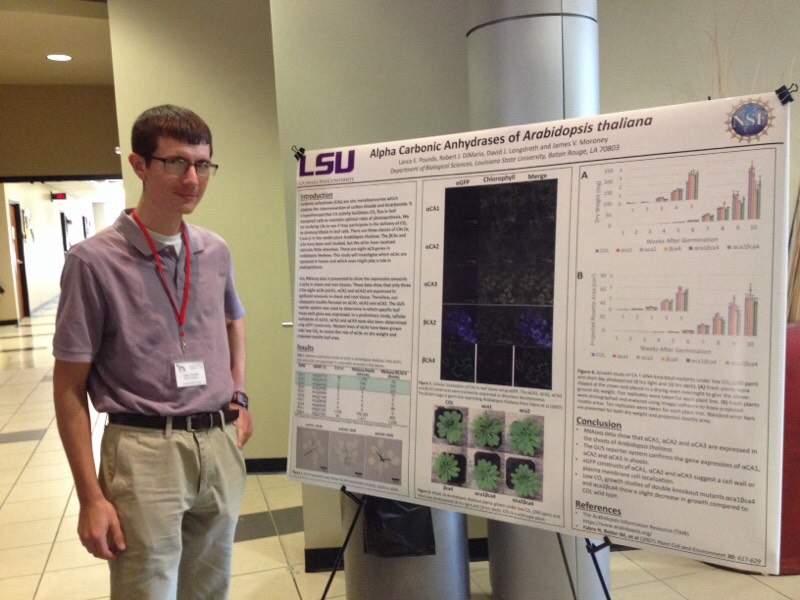 Lance standing in front of poster titled "Alpha Carbonic Anhydrases of Arabidopsis thaliana"