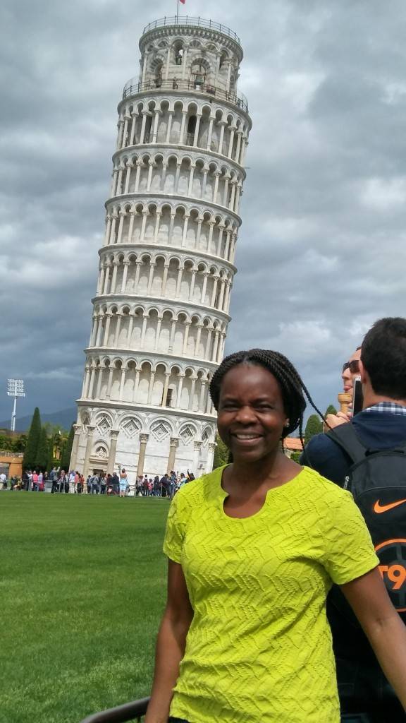 Mary smiling standing in front of the Leaning Tower of Pisa
