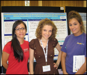 Kathie L., Yohana G., and Lauren E-F. posing in front of poster