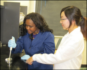 Rasheda G. holds micropipette over petri dish as and LuLu gestures