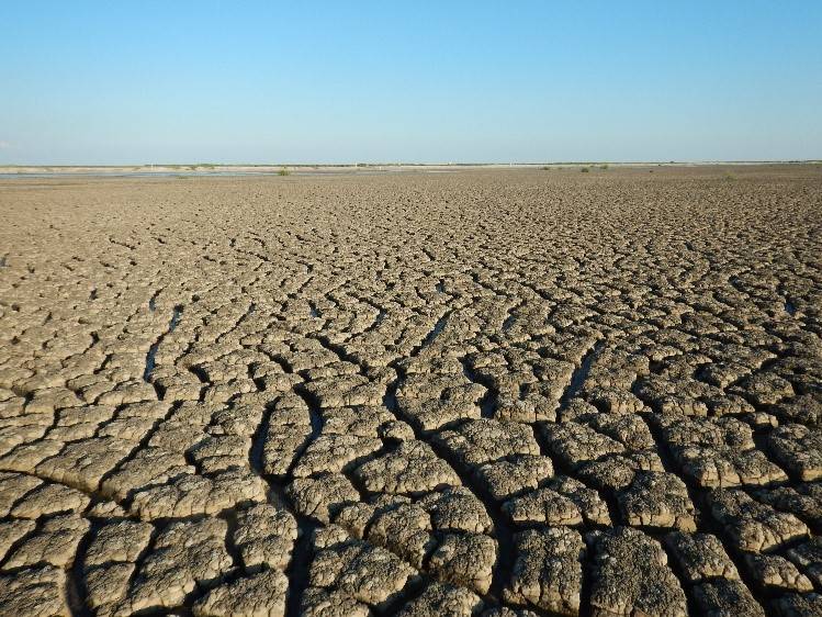 Vast expanse of dry caked mud with blue skies above.