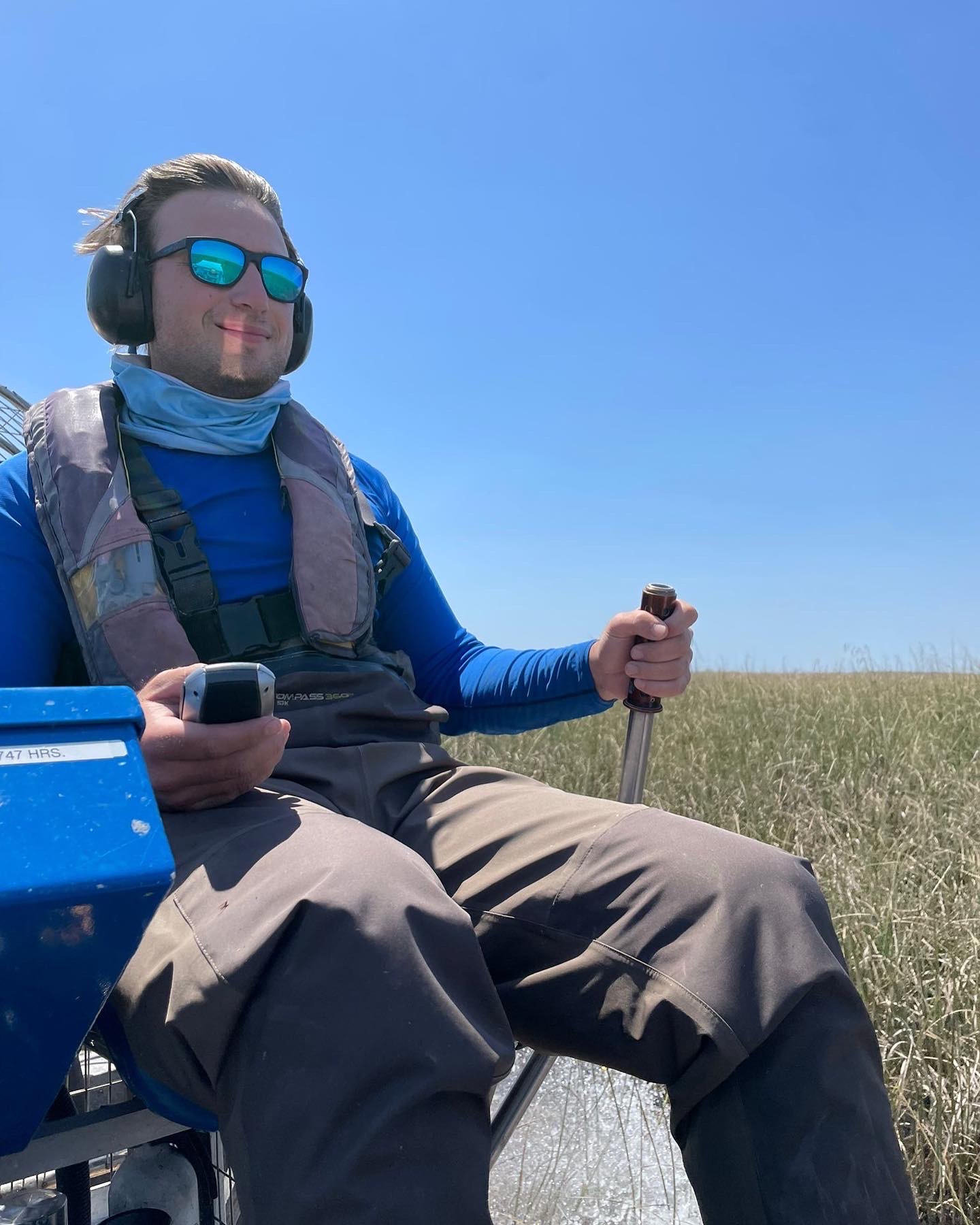 Man driving an airboat, wearing sunglasses