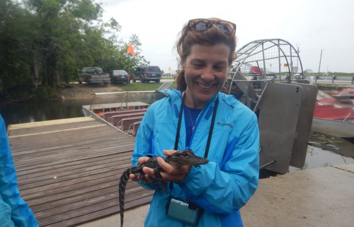 Dr. Tracy Quirk holds a small crocodile on a boat dock.