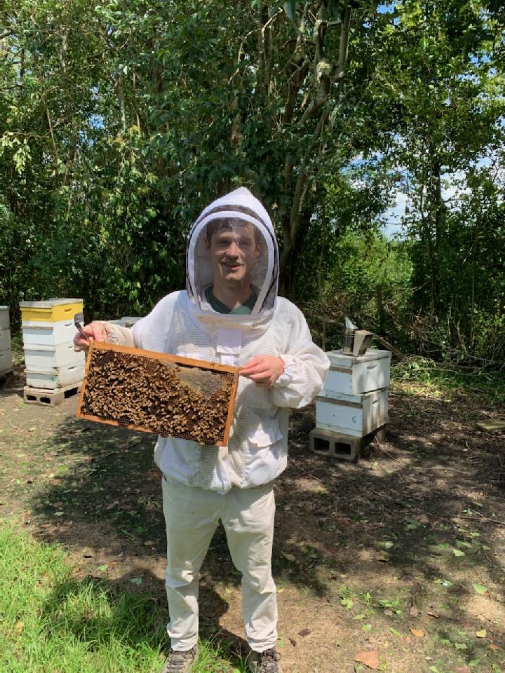 Image of Tyler Williams in a bee suit with bees