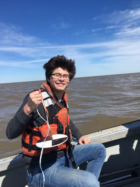 a man holds up a wire while seated on a boat